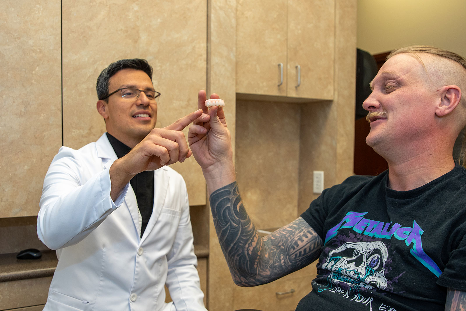patient and doctor looking at full arch dental implant model