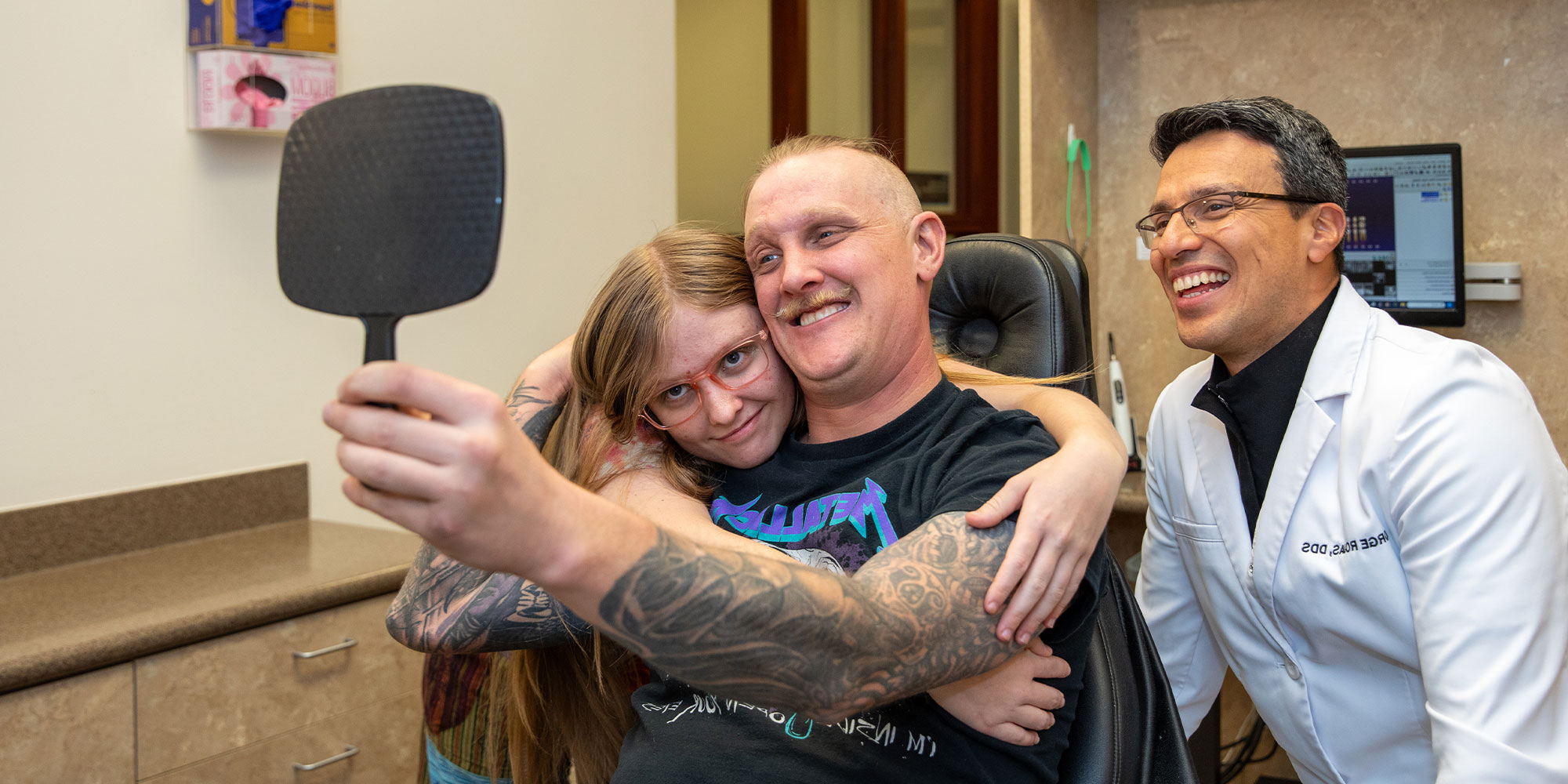 patient smiling brightly with their daughter after dental implant treatment